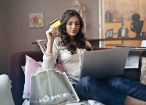 Topinabee Debt Solutions woman holding card while operating silver laptop 919436 300x215